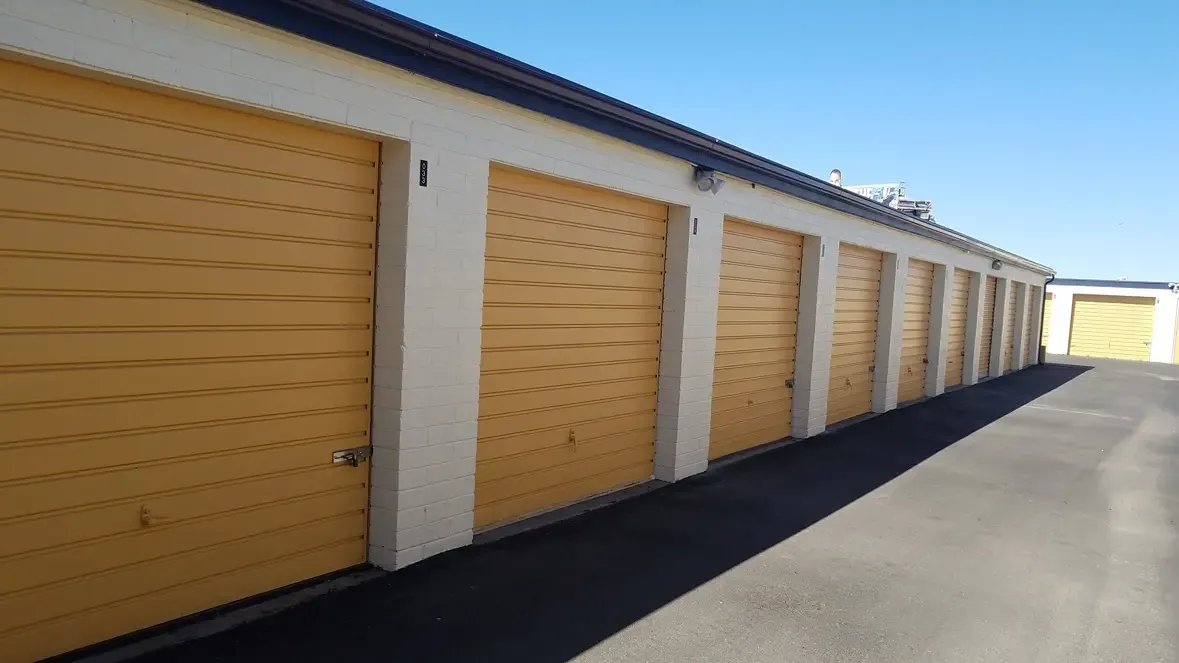yellow door drive up storage units with asphalt driveway.